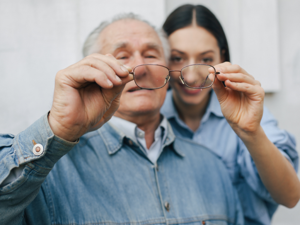 Old man standing with his daughter holding pair of glasses